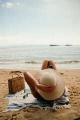 Caucasian girl tanning on beach wearing straw sunhat 