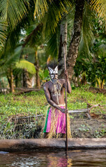 Warrior of the Asmat tribe in a traditional mask on a canoe.