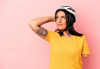 Young caucasian woman with one arm wearing a bike helmet isolated on pink background touching back of head, thinking and making a choice.