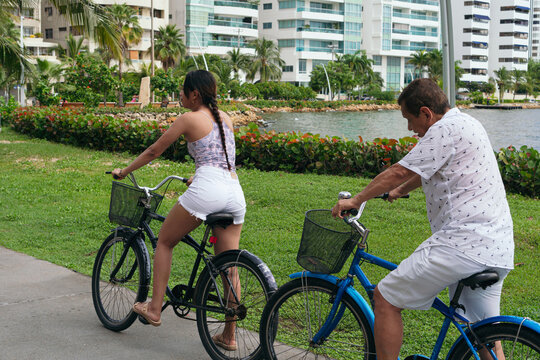 Latino Family Riding Bicycles In City Park