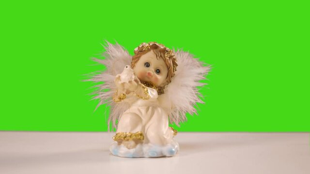 a statuette of an angel stands on the table. green background