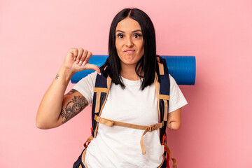 Young caucasian hiker woman with one arm isolated on pink background showing a dislike gesture, thumbs down. Disagreement concept.