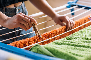 Woman hanging clean laundry with clothespins on washing line outdoors, closeup