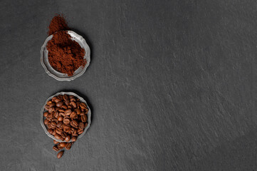 Two plates of coffee. one with coffee beans and the other with ground coffee on a black background copy space