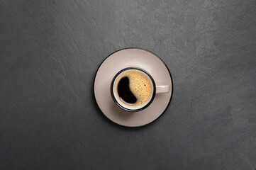 a cup of coffee with beautiful foam near coffee beans are scattered on a black stone background top view copy space