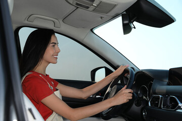 Fototapeta na wymiar Beautiful young woman driving her modern car