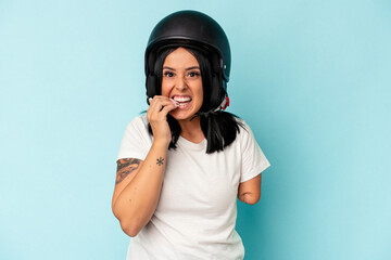 Young caucasian woman with one arm wearing a motorcycle helmet isolated o blue background biting fingernails, nervous and very anxious.
