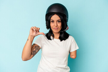 Young caucasian woman with one arm wearing a motorcycle helmet isolated o blue background showing a dislike gesture, thumbs down. Disagreement concept.