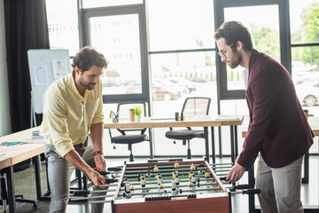 Businessmen in formal wear playing table soccer in office
