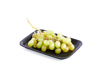Cluster of green grapes on a black tray on a white background. Healthy food concept