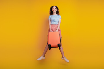 Fototapeta na wymiar Full length photo of young attractive woman happy positive smile bag suitcase travel fly jump isolated over yellow color background