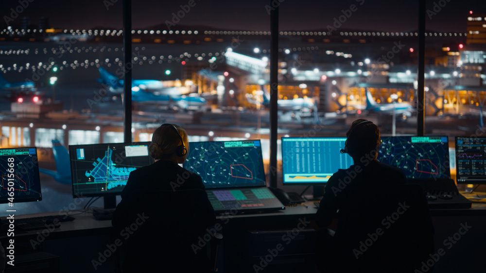 Wall mural Diverse Air Traffic Control Team Working in a Modern Airport Tower at Night. Office Room is Full of Desktop Computer Displays with Navigation Screens, Airplane Flight Radar Data for Controllers.