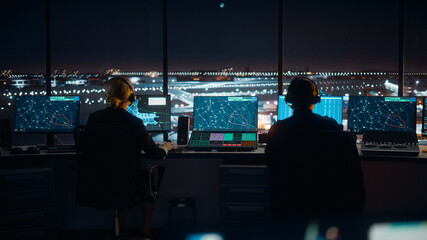 Diverse Air Traffic Control Team Working in a Modern Airport Tower at Night. Office Room is Full of Desktop Computer Displays with Navigation Screens, Airplane Flight Radar Data for Controllers.