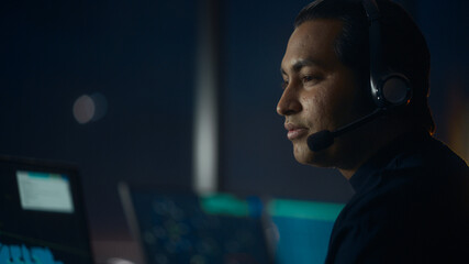 Close Up Portrait of Male Air Traffic Controller with Headset Talk on a Call in Airport Tower. Office Room is Full of Desktop Computer Displays with Navigation Screens, Airplane Flight Radar Data. © Gorodenkoff