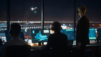 Female and Male Air Traffic Controllers with Headsets Talk in Airport Tower at Night. Office Room Full of Desktop Computer Displays with Navigation Screens, Airplane Flight Radar Data for Controllers. - obrazy, fototapety, plakaty