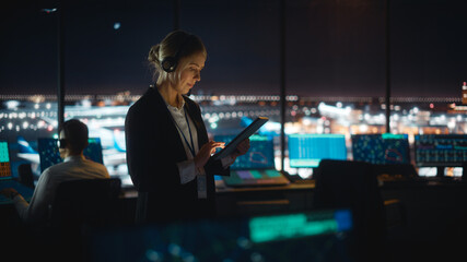 Caucasian Female Air Traffic Controller Working on Tablet in Airport Tower. Office Room is Full of...
