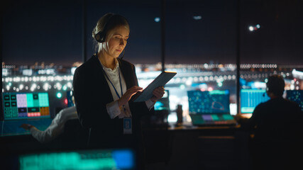 Caucasian Female Air Traffic Controller Working on Tablet in Airport Tower. Office Room is Full of...