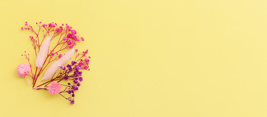Top view image of pink and purple flowers composition over pastel yellow background .Flat lay