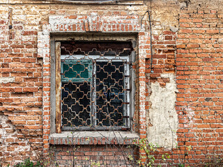 Window with a figured lattice on the wall of an old brick house