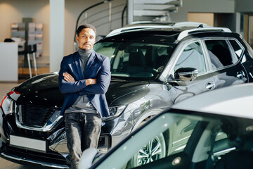 Confident african man standing near luxury car at salon