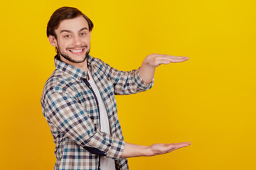 Profile side phot oo f young man gesturing with hands big and large size sign measure symbol smiling isolated over yellow color background