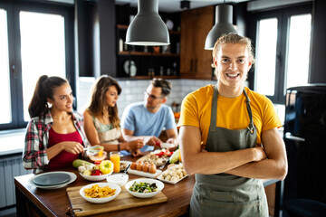 Beautiful happy people, friends is smiling while cooking together in the kitchen