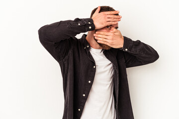 Young caucasian man with diastema isolated on white background blink at the camera through fingers, embarrassed covering face.