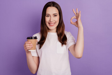 Fototapeta premium Photo of young girl enjoy cup of coffee show oakey perfect choose sign isolated over violet color background