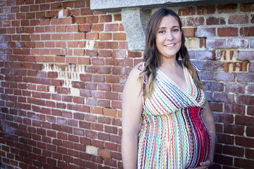 Seven month pregnant woman outdoors in multi colored striped dress