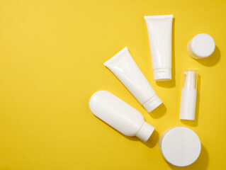 jar, bottle and empty white plastic tubes for cosmetics on a yellow background. Packaging for cream, gel, serum, advertising and product promotion