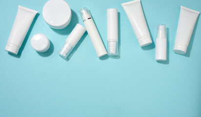 jar, bottle and empty white plastic tubes for cosmetics on a blue background. Packaging for cream, gel, serum, advertising and product promotion