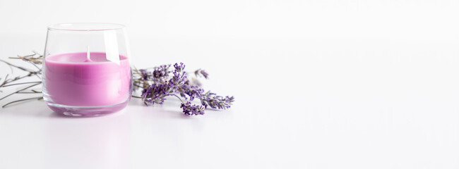 Aroma candles with colorful wax in glass with sprig of dry lavender on white background. banner