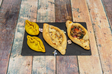 Corn and wheat patties with meat vegetables, melted fresh cheese on black slate plate