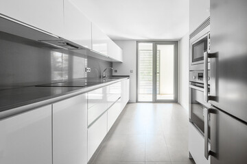View of a kitchen with white cabinets, gray synthetic stone countertop and stainless steel...