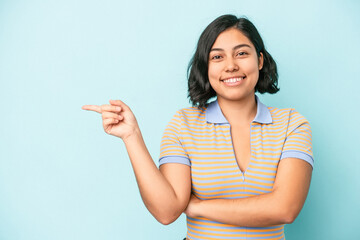 Young latin woman isolated on blue background smiling cheerfully pointing with forefinger away.