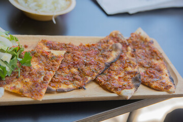 Lahmacun, a round, thin piece of dough topped with minced meat (most commonly beef or lamb), minced vegetables and herbs 
