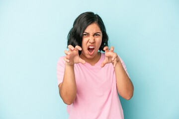 Young latin woman isolated on blue background showing claws imitating a cat, aggressive gesture.