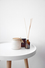 Small round coffee table with a candle and perfume for rooms on a white background.