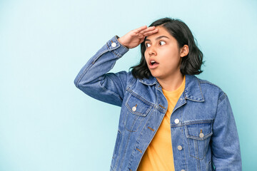 Young latin woman isolated on blue background looking far away keeping hand on forehead.