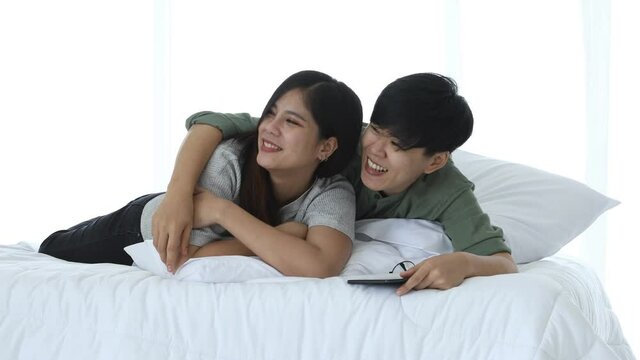 Happy Asian lesbian couple leisure activity concept, elder glasses female point out younger woman asking question on bed