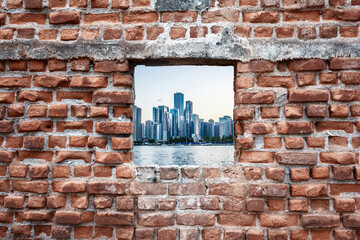 Ruined old brick wall window with sea and skyscrapers view. Urbanization
