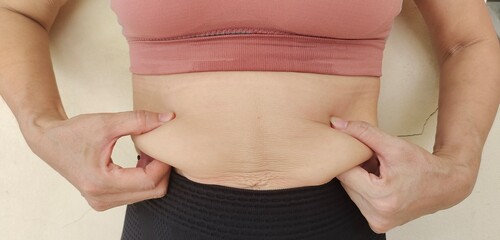 close up of a person holding a stomach, the hands squeezing around the waist of belly.