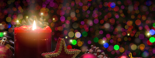 Advent candle with Christmas decorations and lights background.