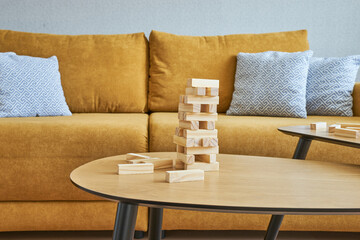 A yellow Scandinavian-style sofa with a wooden tower game on the coffee table
