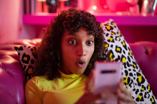 Young adult female looking shocked at a smartphone
