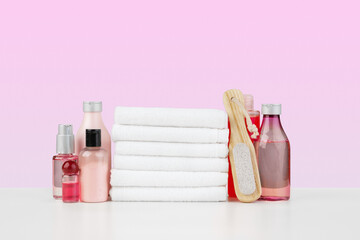 Stack of white towels and bottles of skincare on white table
