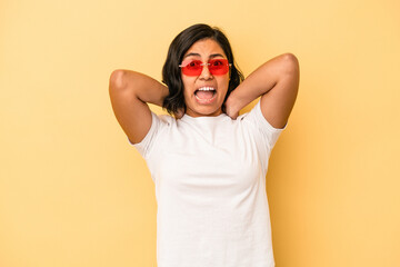 Young latin woman isolated on yellow background screaming with rage.