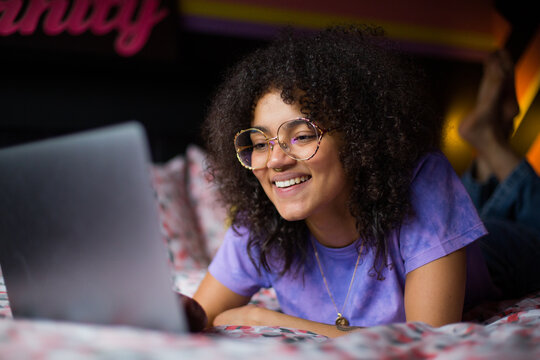 Young adult gen z female student using a laptop in her bedroom