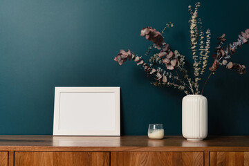 Blank picture frame mockup on green wall. View of modern scandinavian style interior with artwork mock up on wall