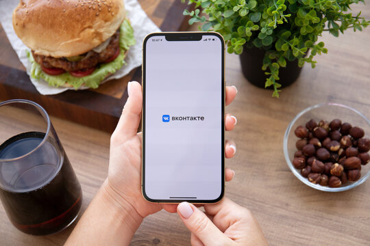 Woman hand holding iPhone 12 Pro Max Gold with VKontakte